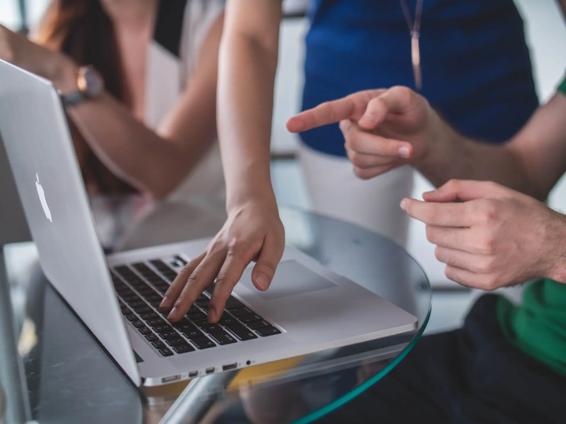 Mehrere Menschen zeigen mit ihren Fingern auf das Display eines Laptops.